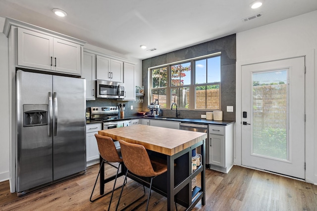 kitchen with decorative backsplash, appliances with stainless steel finishes, sink, white cabinets, and light hardwood / wood-style floors