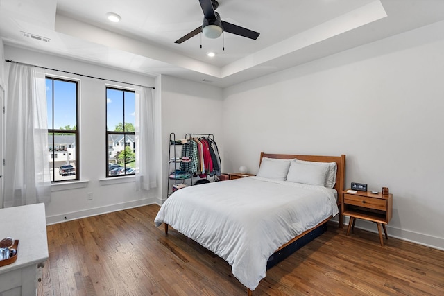 bedroom featuring ceiling fan, a raised ceiling, and dark wood-type flooring