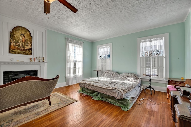 bedroom with ceiling fan, wood-type flooring, and crown molding