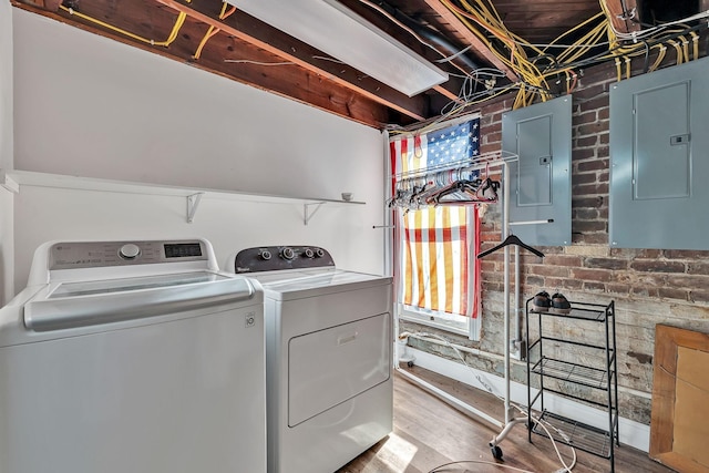 laundry area featuring washer and dryer, brick wall, a healthy amount of sunlight, and electric panel