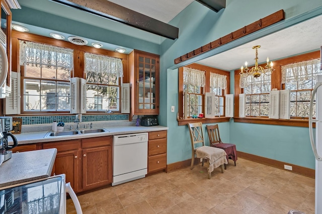 kitchen with a notable chandelier, white dishwasher, sink, tasteful backsplash, and decorative light fixtures