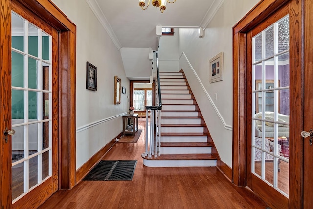 entryway with a chandelier, wood-type flooring, french doors, and crown molding