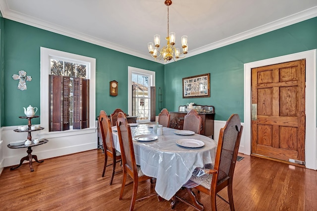 dining room with hardwood / wood-style flooring, an inviting chandelier, and ornamental molding