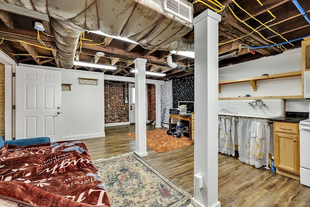 basement featuring hardwood / wood-style flooring and brick wall