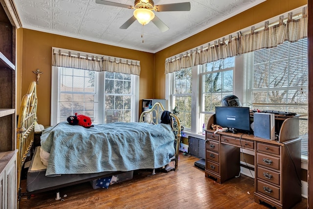 bedroom with ceiling fan, crown molding, and dark wood-type flooring