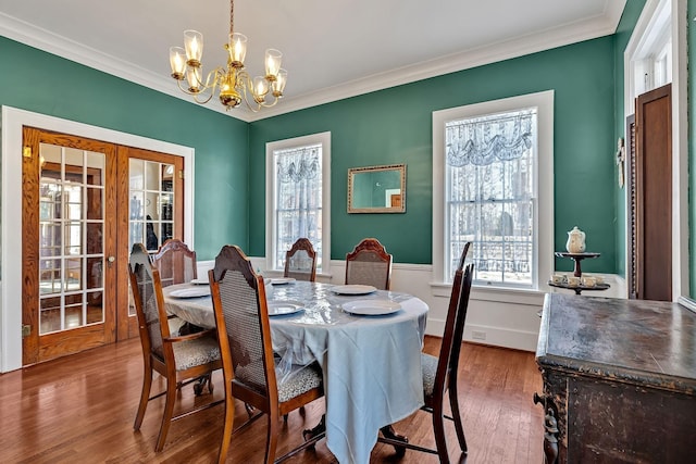 dining area featuring hardwood / wood-style floors, french doors, ornamental molding, and a chandelier