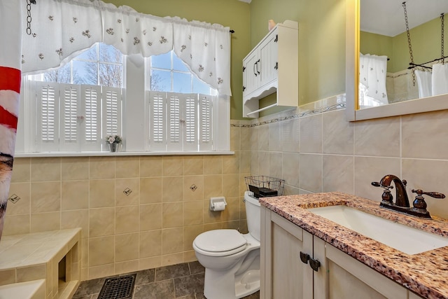 bathroom featuring vanity, a shower with curtain, tile patterned flooring, toilet, and tile walls