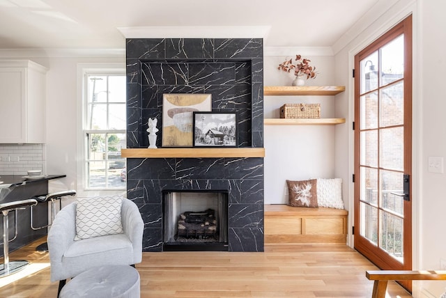 living room featuring a premium fireplace, ornamental molding, and light wood-type flooring