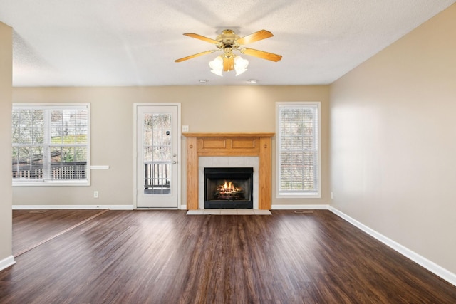 unfurnished living room featuring a tile fireplace, ceiling fan, dark hardwood / wood-style flooring, and a textured ceiling