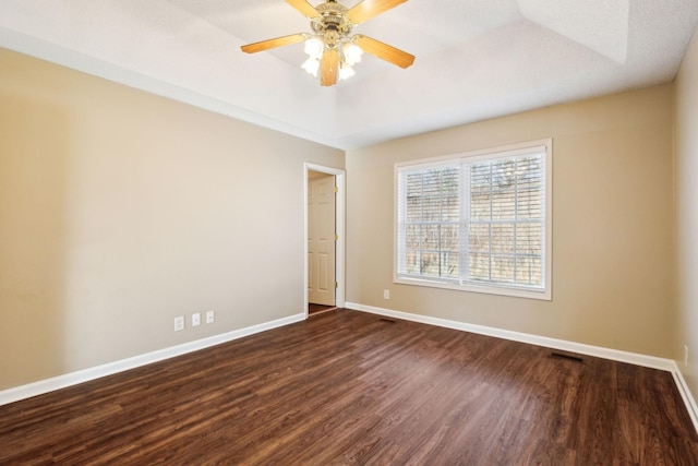 unfurnished room with dark hardwood / wood-style flooring, a raised ceiling, and ceiling fan