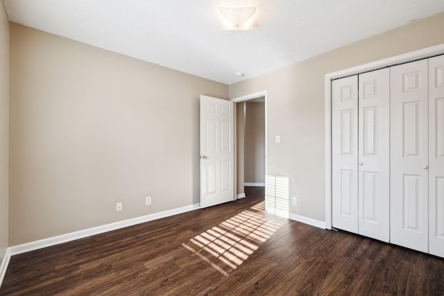 unfurnished bedroom with a textured ceiling, dark hardwood / wood-style floors, and a closet