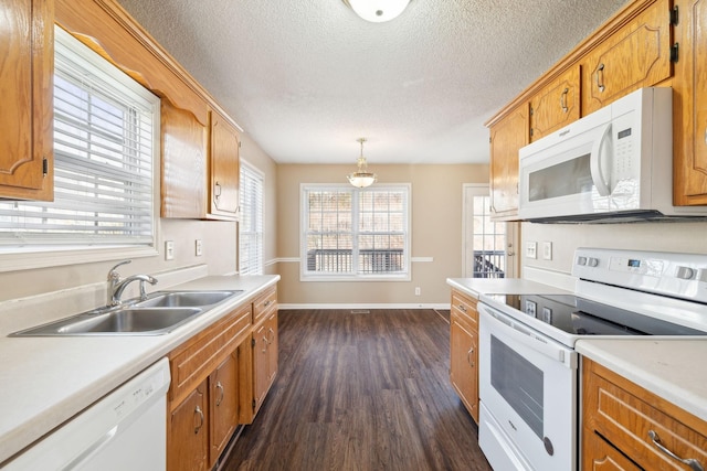 kitchen with sink, dark hardwood / wood-style flooring, a textured ceiling, decorative light fixtures, and white appliances