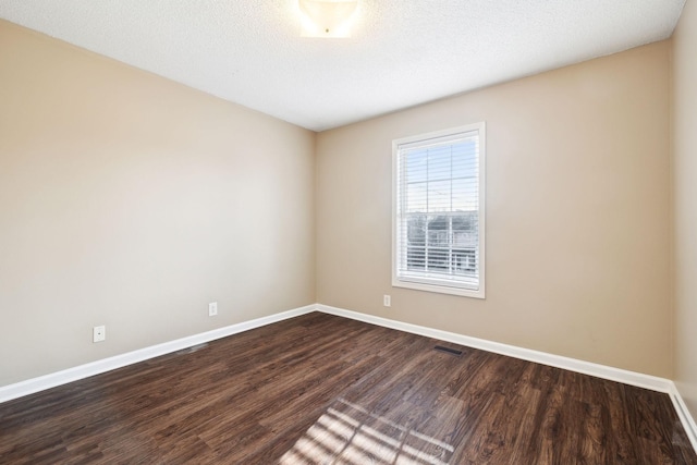 spare room featuring a textured ceiling and dark wood-type flooring