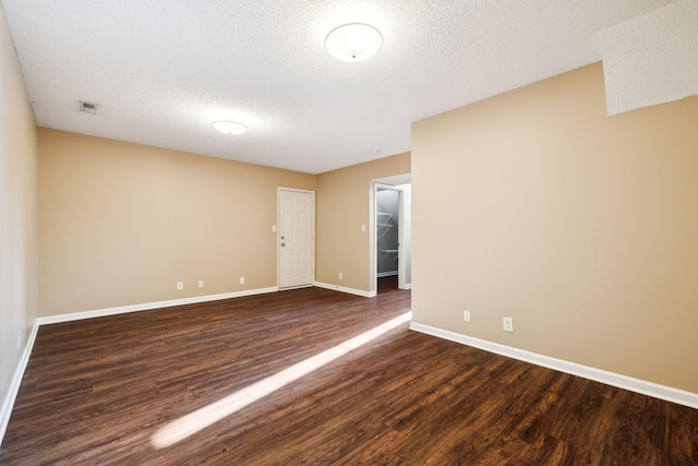 empty room with a textured ceiling and dark hardwood / wood-style flooring