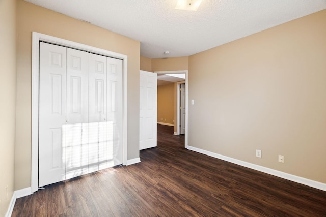 unfurnished bedroom with a textured ceiling, a closet, and dark hardwood / wood-style floors