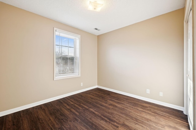 empty room with a textured ceiling and dark hardwood / wood-style floors