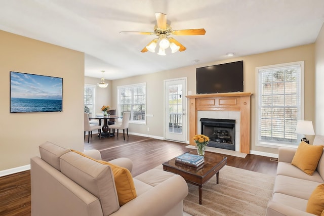 living room featuring a tile fireplace, a wealth of natural light, dark hardwood / wood-style flooring, and ceiling fan