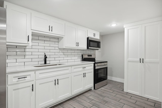 kitchen featuring white cabinets, appliances with stainless steel finishes, light hardwood / wood-style floors, and sink