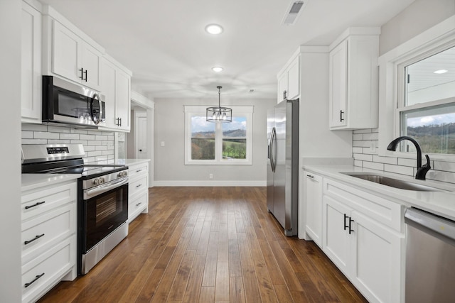 kitchen featuring appliances with stainless steel finishes, backsplash, dark hardwood / wood-style flooring, sink, and white cabinets