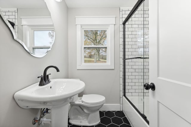 bathroom with bath / shower combo with glass door and toilet