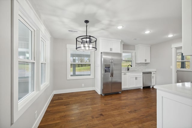 kitchen with decorative backsplash, dark hardwood / wood-style flooring, stainless steel appliances, white cabinetry, and hanging light fixtures