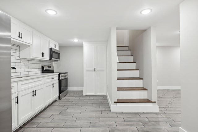 kitchen featuring decorative backsplash, white cabinetry, sink, and appliances with stainless steel finishes