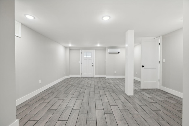 basement with light hardwood / wood-style flooring and a wall mounted AC