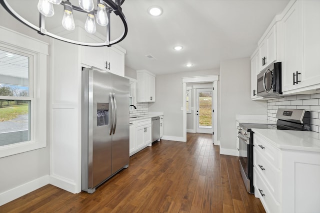 kitchen with white cabinets, appliances with stainless steel finishes, backsplash, and an inviting chandelier