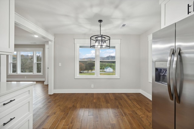 unfurnished dining area featuring an inviting chandelier and dark wood-type flooring