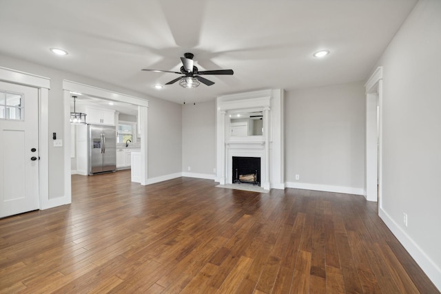 unfurnished living room featuring dark hardwood / wood-style floors and ceiling fan