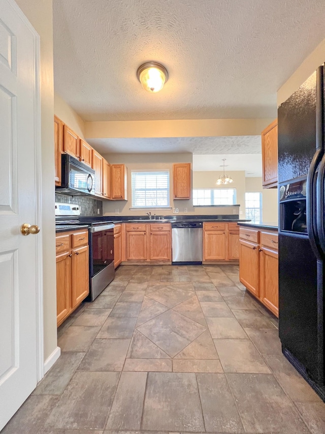 kitchen with sink, hanging light fixtures, tasteful backsplash, a chandelier, and black appliances