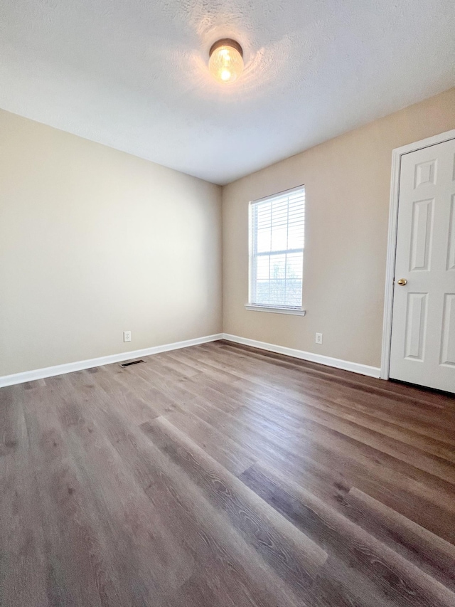 unfurnished room featuring dark hardwood / wood-style flooring and a textured ceiling