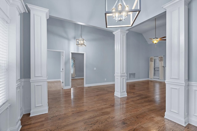 interior space with dark hardwood / wood-style flooring, ceiling fan with notable chandelier, high vaulted ceiling, and ornate columns