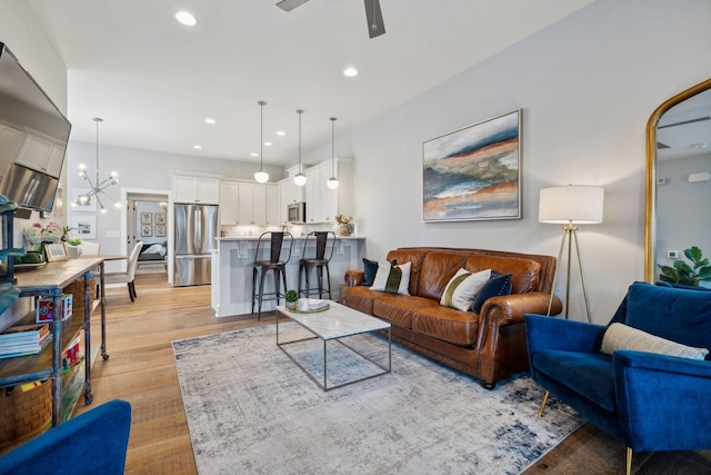 living room with light hardwood / wood-style floors and ceiling fan with notable chandelier