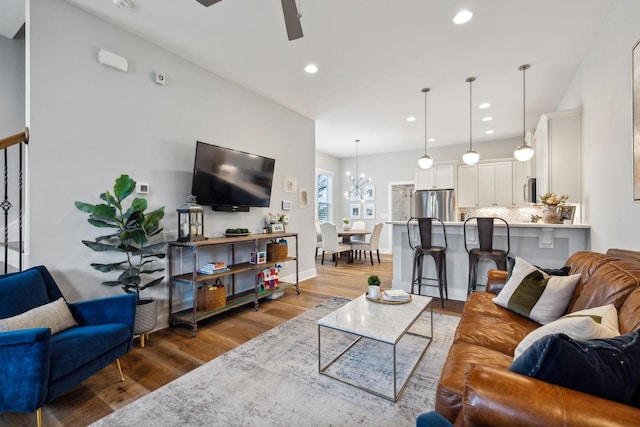 living room featuring hardwood / wood-style flooring and ceiling fan with notable chandelier