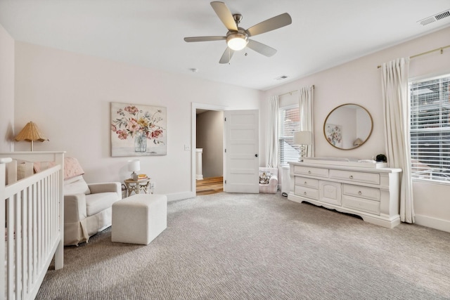 carpeted bedroom with a nursery area and ceiling fan