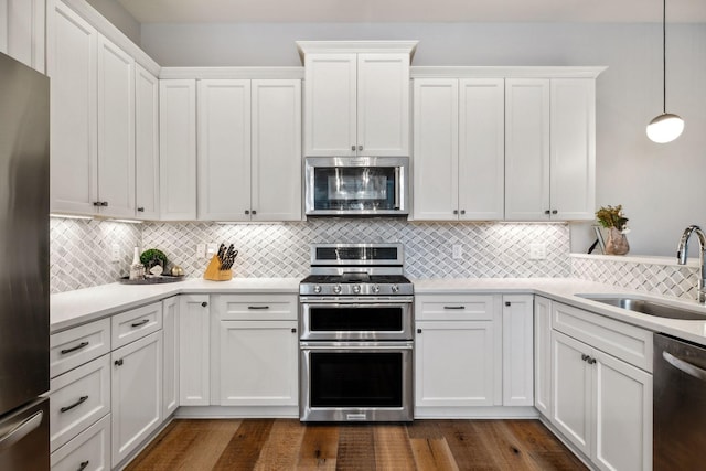 kitchen with white cabinetry, sink, hanging light fixtures, and appliances with stainless steel finishes