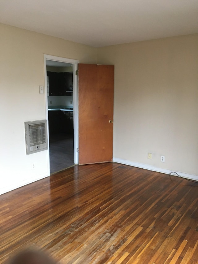 empty room with dark hardwood / wood-style floors and heating unit