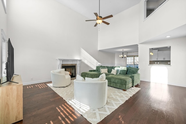 living room featuring ceiling fan with notable chandelier, hardwood / wood-style floors, a high end fireplace, and a high ceiling