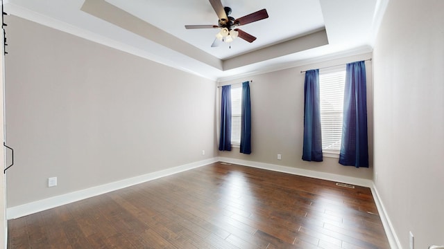 unfurnished room with a tray ceiling, ceiling fan, and dark wood-type flooring