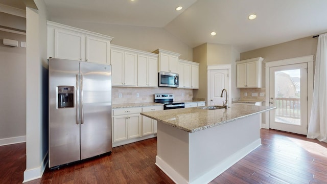 kitchen with tasteful backsplash, stainless steel appliances, sink, white cabinets, and an island with sink