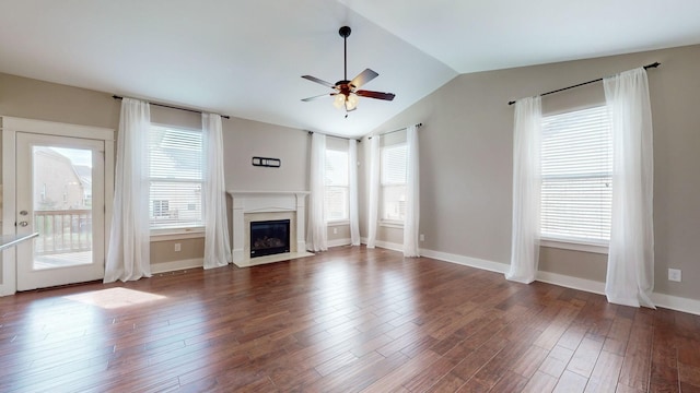 unfurnished living room with plenty of natural light, a premium fireplace, dark wood-type flooring, and lofted ceiling