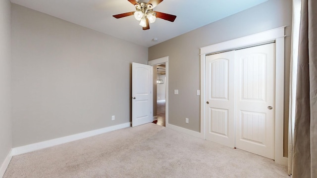 unfurnished bedroom with ceiling fan, light colored carpet, and a closet