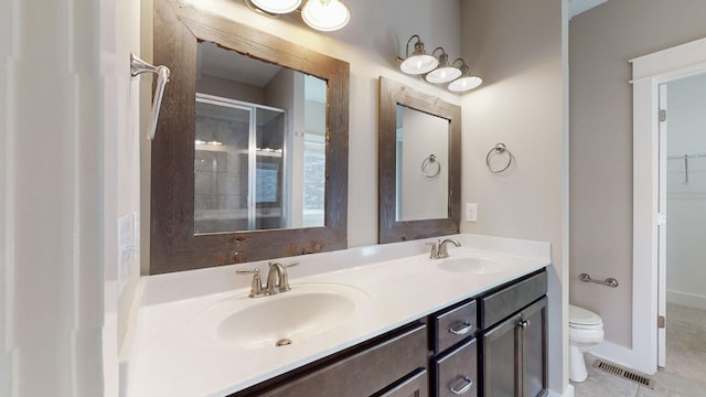 bathroom with tile patterned flooring, vanity, toilet, and an enclosed shower