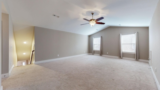 empty room with ceiling fan, light colored carpet, and vaulted ceiling