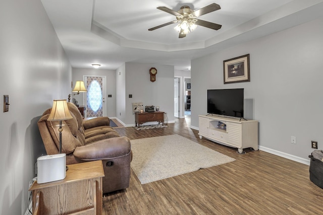 living room with ceiling fan, dark hardwood / wood-style flooring, and a raised ceiling