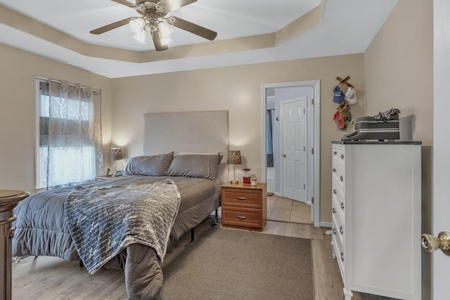 bedroom featuring a tray ceiling, ceiling fan, and light hardwood / wood-style floors