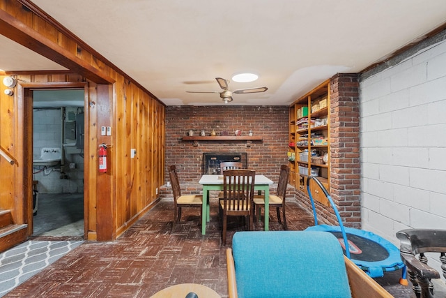 dining area featuring ceiling fan, ornamental molding, and wooden walls