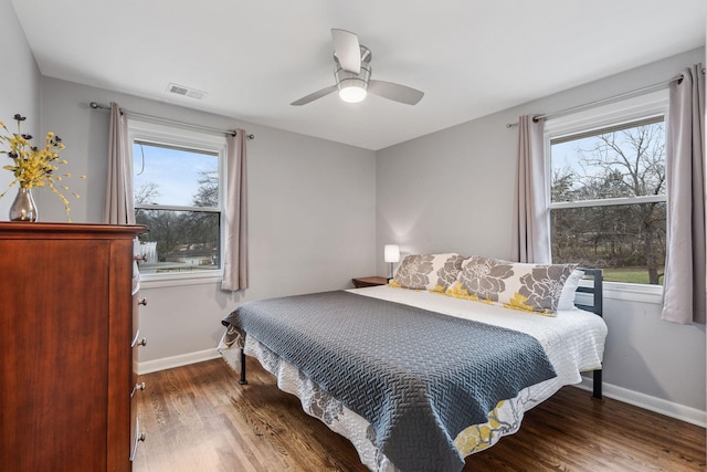 bedroom featuring ceiling fan, dark hardwood / wood-style floors, and multiple windows