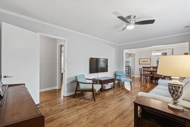 living room featuring hardwood / wood-style floors, ceiling fan with notable chandelier, and ornamental molding